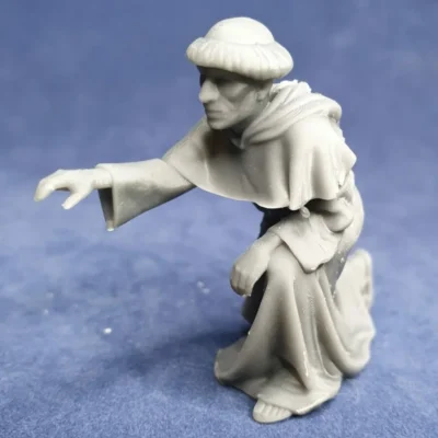 Monk kneeling picking fruit in garden hood on back